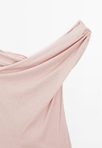 Lyserød top med off-shoulder design, lavet af ribbet stof. Har samlede ærmer og en blød, tekstureret overflade.