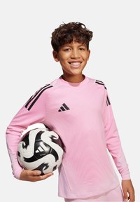 Maglia a maniche lunghe rosa con dettagli neri e logo Adidas, abbinata a un pallone da calcio bianco e nero con un motivo a spirale.