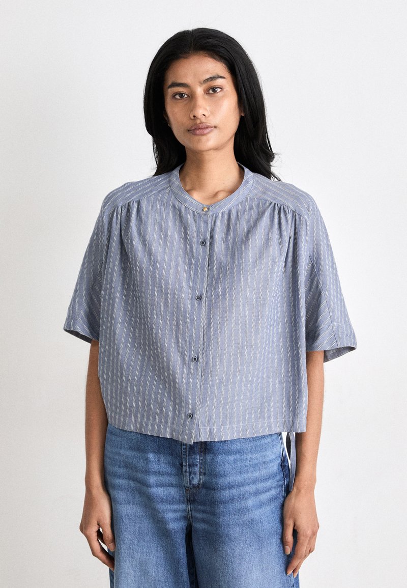 Blauw gestreepte blouse met korte mouwen en een ronde halslijn, voorzien van knoopsluitingen en geplooide details langs de schouders.