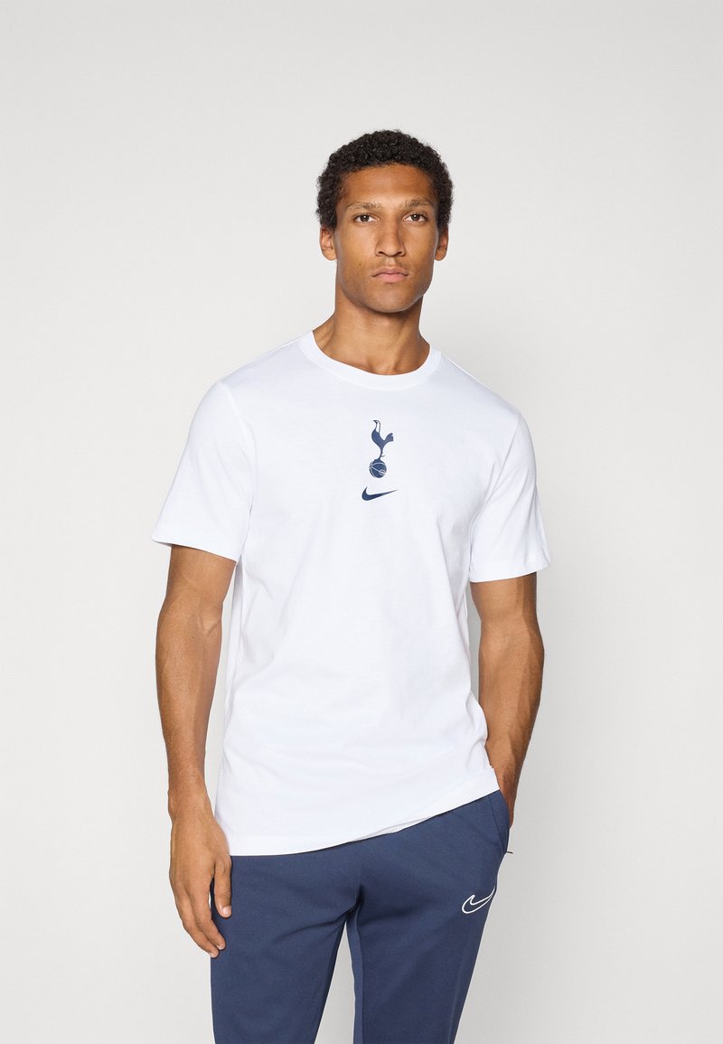 Hvid bomulds T-shirt med et blåt Tottenham Hotspur logo og en blå Nike swoosh på forsiden. Kortærmede og med rund halsudskæring.