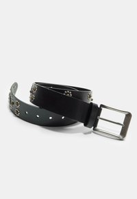 Zwarte leren riem met zilveren bloemvormige studs en een rechthoekige metalen gesp op een witte achtergrond.