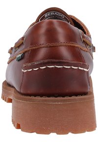 Braune Lederbootsschuhe mit abgerundetem Fersenbereich, weißen Nähten, Metallösen und einer strukturierten Gummisohle für besseren Grip. Markenlogo auf der Zunge.