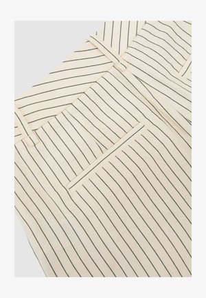 Beige nadrág közeli képe vékony, függőleges fekete csíkokkal, övbújtatókkal és hátsó paszpólos zsebbel.