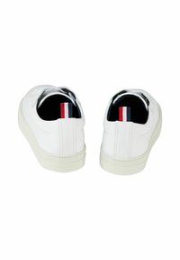 Weiße Schuhe mit einer glatten Lederoberfläche, runder Zehenpartie und gepolstertem Absatz. An der Rückseite befindet sich ein farbiger Streifen in Rot, Weiß und Blau.