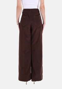 Pantaloni marroni a gamba larga in velluto a coste con vita alta, dotati di due tasche posteriori e una finitura strutturata. Design minimalista, gambe a taglio dritto.