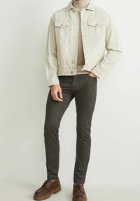 Světlá džínová bunda s kapsami na prsou, béžový rolák, tmavé přiléhavé kalhoty a hnědé šněrovací boty. Ležérní outfit.