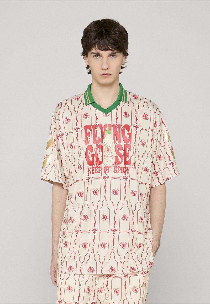 Chemise crème à manches courtes avec un motif de bouteilles rouges et de roses, col côtelé vert, et texte audacieux "Flying Goose Keep It Spicy".