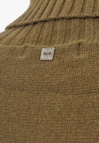 Maglione a maglia verde oliva con texture a coste, cuciture orizzontali e un'etichetta logo argentata con testo inciso.