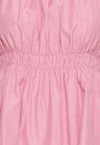 Tissu rose avec de fines rayures blanches verticales et un détail de fronces élastiques créant une texture froncée.