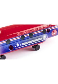 Red metal transport helicopter model with blue accents and white stars. Features black wheels and "TRANSPORT HELICOPTER" text on side.