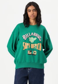 Felpa oversize verde con la scritta "BILLABONG", "SURF AFRICA" e "1640" in colori audaci e contrastanti, con un carattere giocoso. Vestibilità rilassata e polsini a coste.