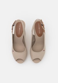 Scarpe beige open-toe con una tomaia in tessuto liscio, un accento a fibbia marrone e un taglio rotondo. Cuciture del logo ben visibili sul lato.