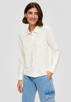Witte blouse met lange mouwen en kraag, voorzien van een knoopsluiting aan de voorkant en een soepele textuur, gecombineerd met lichtblauwe jeans.