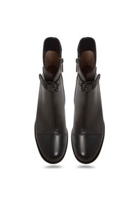 Paire de bottines en cuir noir avec boucles latérales et fermetures éclair, vues de dessus sur fond blanc.