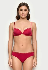 Red lingerie set featuring a lace-trimmed bra with adjustable straps and matching panties. Smooth fabric with a fitted design and subtle accents.