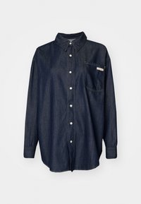 Mørk denim skjorte med knapper som har krage, lange ermer, en enkelt brystlomme og hvite sømdetaljer.
