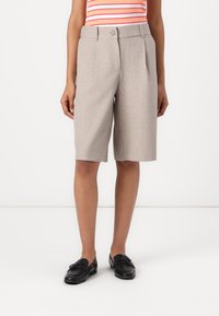 Lys grå skreddersydde shorts med folder, knappelukking og sidelommer, sammen med svarte loafers. Jevn tekstur.