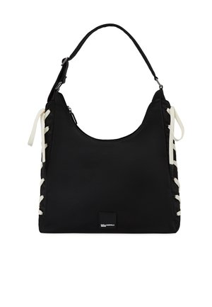 Black shoulder bag with white lace-up sides, single adjustable strap, and small rectangular brand label on front bottom center.