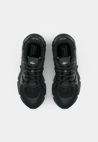 Baskets Lacoste noires avec un design en mesh et cuir, fermeture à lacets, logo de la marque visible sur la languette, vues de dessus.