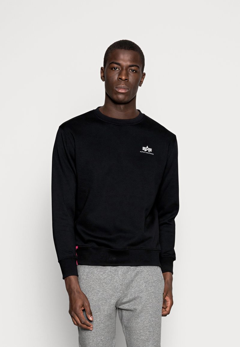 Zwarte sweatshirt van katoen, met een ronde halslijn en lange mouwen. Klein wit logo op de borst, met roze accenten aan de zoom.