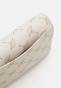 Beige textured bag with embossed pattern of symmetrical shapes, featuring a smooth finish and rounded edges.