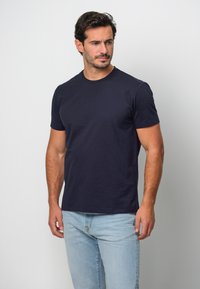 Marinblå bomulls t-shirt med kort ärm och rundad halsringning, tillsammans med ljusblå denimjeans. Enkel design utan mönster eller accent.