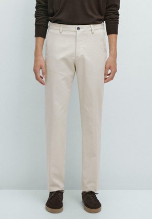 Beige cotton chinos with a straight leg fit, featuring a button closure, side pockets, and subtle texture, paired with dark brown footwear.