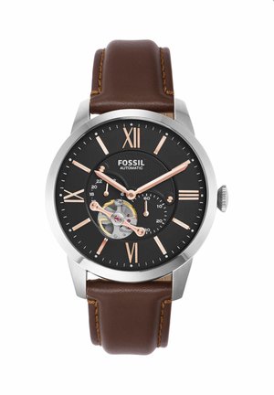 Herren Fossil Automatikuhr mit schwarzem Zifferblatt, roségoldenen römischen Ziffern, sichtbarem Zahnradmechanismus und braunem Lederarmband.