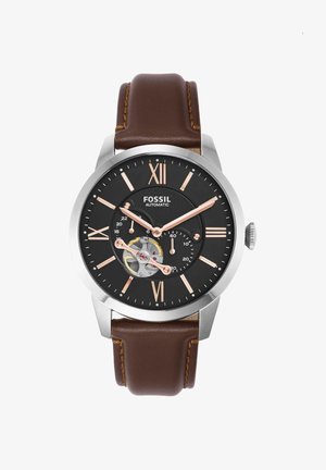 Orologio automatico da uomo Fossil con quadrante nero, numeri romani in oro rosa, meccanismo a ingranaggi visibile e cinturino in pelle marrone.