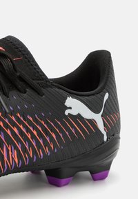 Sort fodboldstøvle med tekstureret overflade, prydet med orange og lilla stribede detaljer. Inkluderer et hvidt Puma-logo og lilla studs.