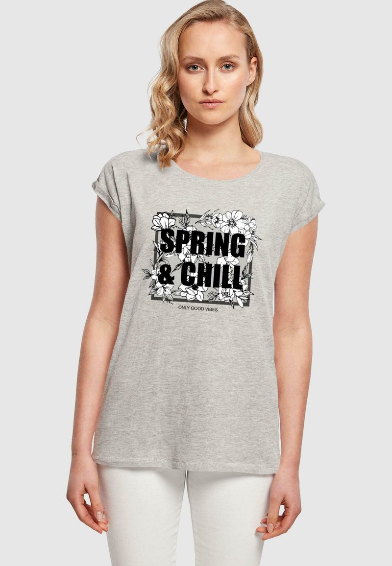 Grå kortærmet t-shirt med et sort blomsterdesign og teksten "SPRING & CHILL" samt "ONLY GOOD VIBES" i fed skrift.