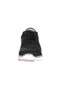 Black athletic shoe with mesh upper, pink accents, white textured sole, and a patterned heel. Features traditional lacing system.