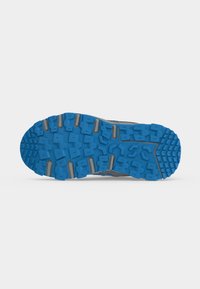 Semelle extérieure en caoutchouc bleu avec des motifs de bande de roulement profonds et multidirectionnels conçus pour la traction sur une chaussure de sport grise.