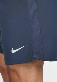 Bermudas deportivas de color azul marino con un panel texturizado, que presentan un logo de Nike blanco en el lateral. Fabricadas con un tejido ligero y transpirable.