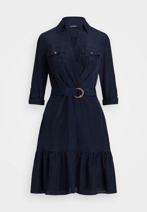 Abito blu navy al ginocchio con colletto, tasche sul petto, maniche tre quarti, vita con cintura e orlo arricciato con volant.