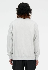 Sudadera gris claro de manga larga y cuello redondo. Presenta puños y dobladillo acanalados, mostrando un diseño texturizado y simple.