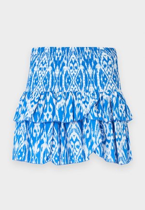 Jupe à motifs bleus et blancs avec une taille smockée, un ourlet à volants superposés et un tissu léger. Présente un design de style ikat.