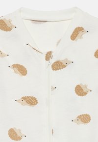 Baumwoll-Einteiler in Creme mit einem Front-Reißverschluss, der ein wiederholtes Igelmuster in Hellbraun und Beige aufweist. Weicher Stoff, keine zusätzlichen Beschläge.