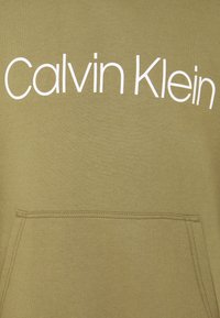 Sweat à capuche vert olive avec un logo "Calvin Klein" blanc sur la poitrine, doté d'une poche avant et de poignets et ourlet côtelés.
