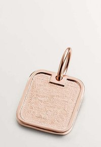 Colgante en forma de etiqueta de oro rosa con una superficie texturizada, esquinas redondeadas y un lazo de metal para su sujeción. Bordes suaves y un sutil brillo.