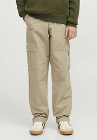 Beige cargobyxor med två sidofickor och en avslappnad passform. Materialet verkar lätt och har en slät textur. Bärs med vita sneakers.