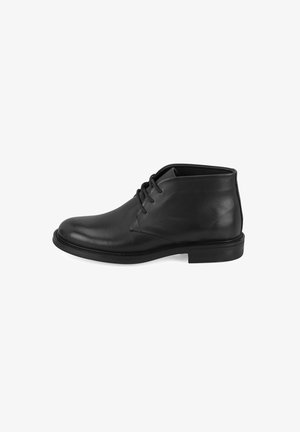 Zwarte leren enkelboots met een ronde neus, lage hak en vetersluiting. Gladde textuur met minimale stiksels en een klassieke silhoutte.