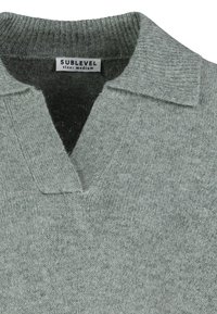 Grauer Strickpullover mit einem gerippten Kragen, halber Knopfleiste und weicher Textur. Das Etikett trägt die Aufschrift "SUBLEVEL" in Größe Medium. Verfügt über ein dezentes Muster.