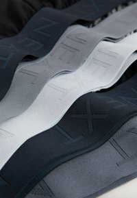 Bandes élastiques en noir, gris foncé, gris clair et blanc cassé, présentant un motif texturé et une finition lisse, disposées en couches.