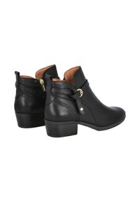 Botines de cuero negro con tacón bajo, que cuentan con una cremallera lateral, detalle de correa con hebilla y textura suave. Forrados en beige.