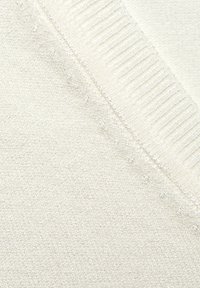 Cremefarbener Strickstoff mit strukturiertem Finish, einem gerippten Rand und subtilen, eingewebten Mustern auf der gesamten Oberfläche.