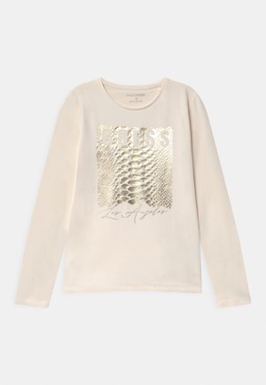 Langærmet cremefarvet skjorte med metallic guld slangeskind firkant, "GUESS" tekst over og "Los Angeles" skrift nedenfor på forsiden.