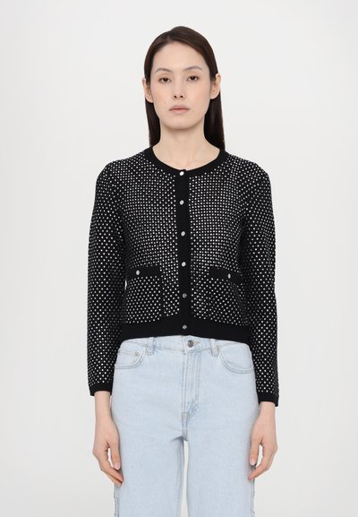 Sort cardigan med sølvprikket mønster, rund hals, knaplukning og ribbede manchetter. Har to foran lommer. Tekstureret strikstof.
