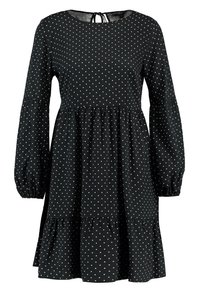 Vestido negro con mangas largas de globo, escote redondo y una falda en capas. Presenta lunares blancos por toda la prenda y un detalle de lazo en la parte posterior.