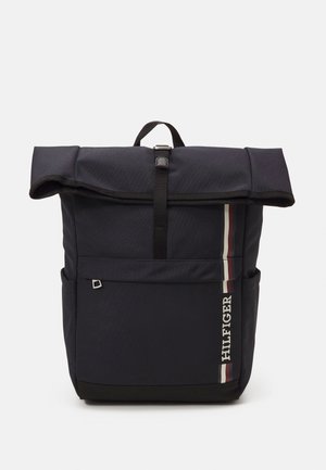 Czarny plecak typu roll-top z przednią kieszenią, pionowymi czerwonymi, białymi i niebieskimi paskami oraz logo "HILFIGER" na szarym tle.